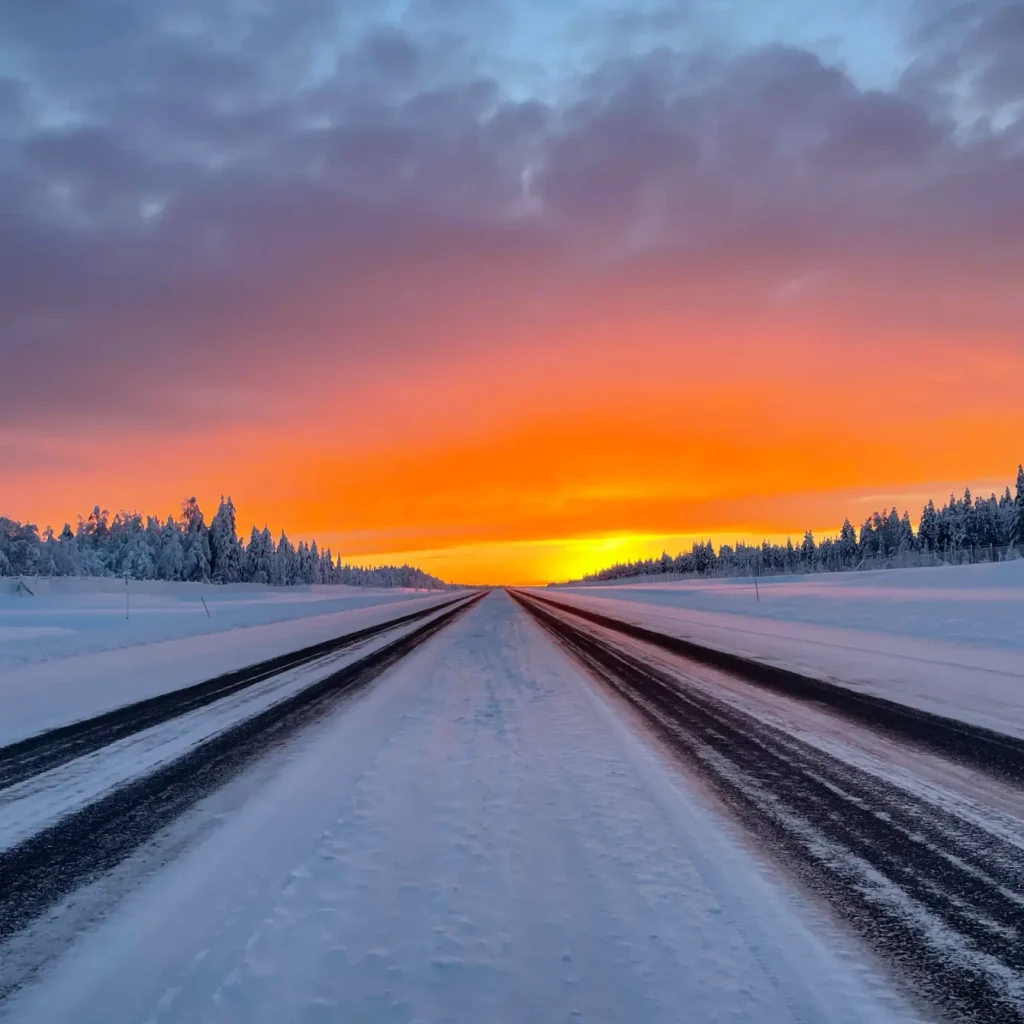 Snowy road in Rovaniemi Lapland during winter, with a golden sunset during the polar night season